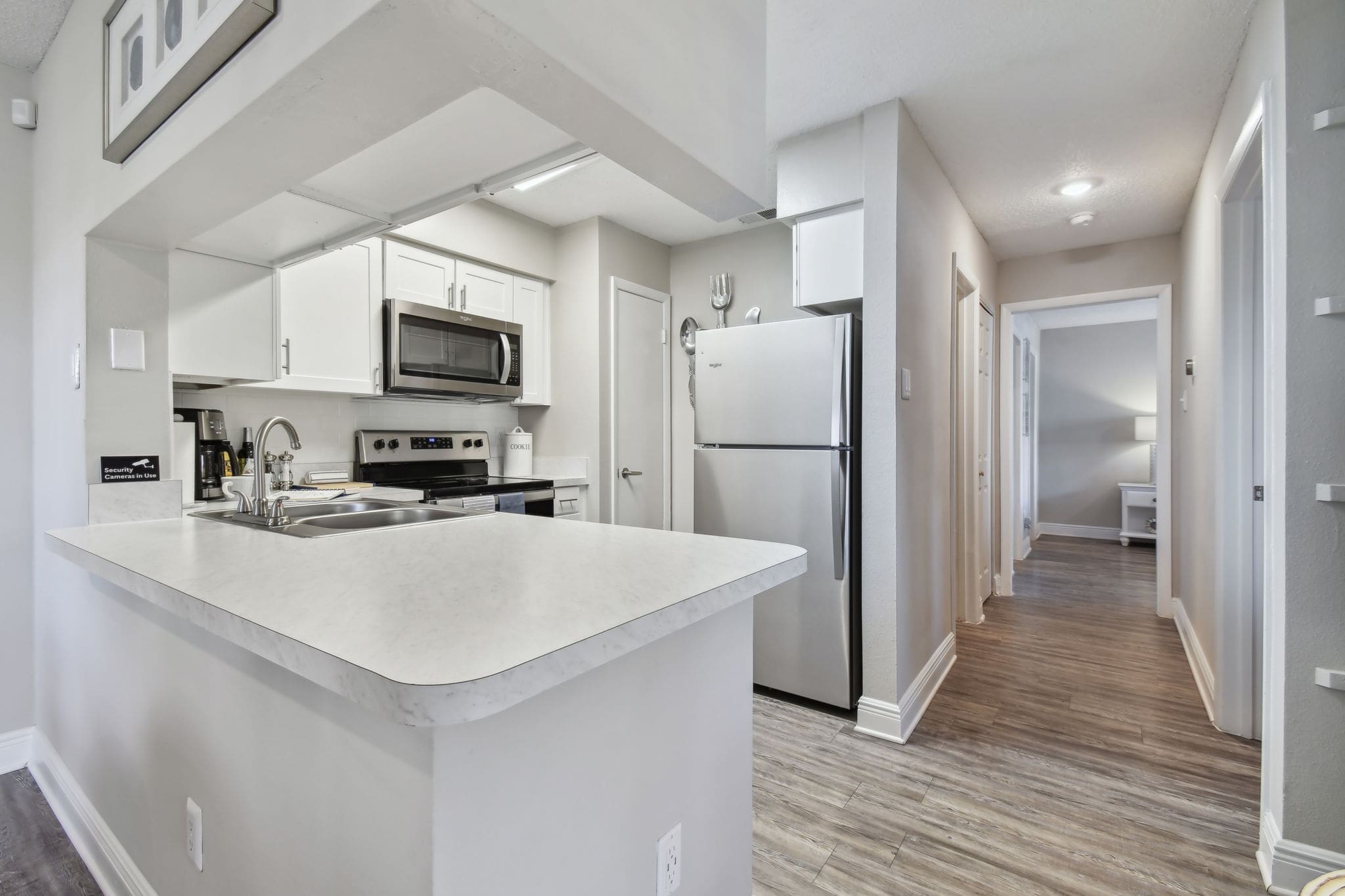 Largo, FL, Apartments Near Clearwater Beach - Enclave on East - Kitchen with Wood-Inspired Flooring, Granite-Style Countertops, Classic Subway Tile Backsplash, White Cabinetry, and Stainless-Steel Appliances.